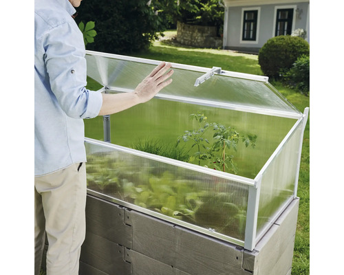 Vyvýšený záhon s pareniskom a osobou v záhrade.