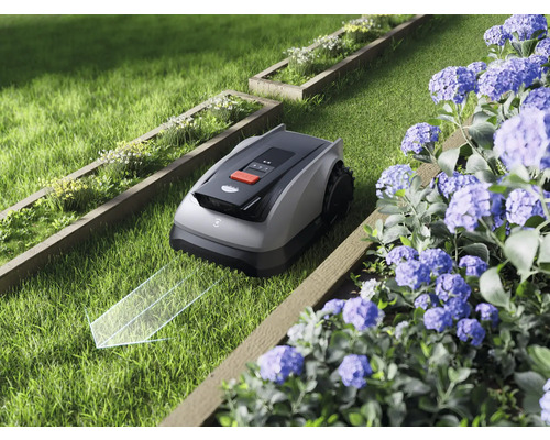 Robotická kosačka na trávu v záhrade s kvetinovými záhonmi a sviežou trávou