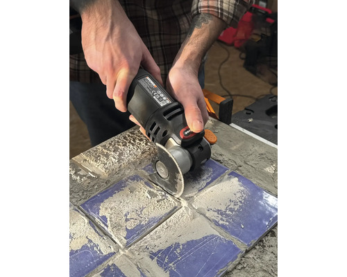 Osoba používa multifunkčný nástroj na rezanie dlaždíc.