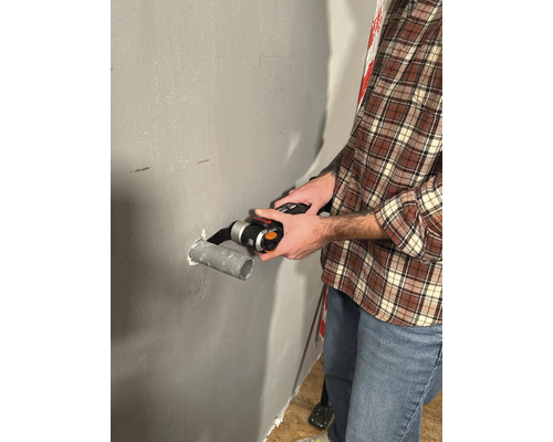 Muž reže rúru multifunkčným nástrojom na stene.