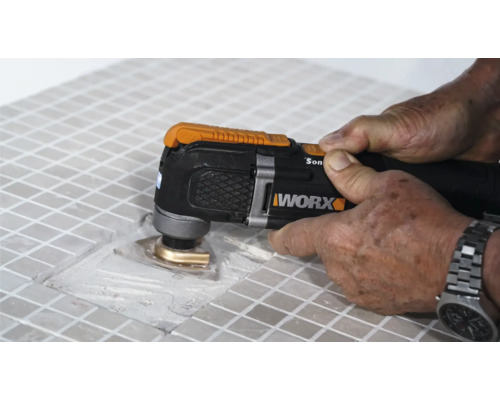 Detailný pohľad na osobu, ktorá opracováva dlaždice multifunkčným nástrojom, značka Worx