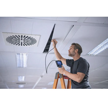 Muž s endoskopom vykonáva inšpekciu stropu na rebríku