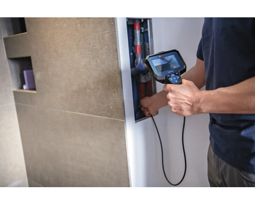 Muž používa inšpekčnú kameru na kontrolu potrubí v kúpeľni.