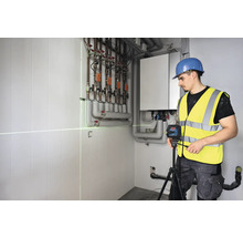 Remeselník používa čiarový laser na vyrovnanie v kotolni.