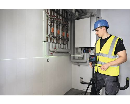 Remeselník používa čiarový laser na vyrovnanie v kotolni.