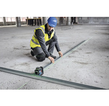 Stavebný robotník niveluje podlahu pomocou čiarového lasera.