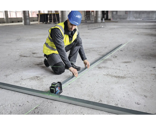 Stavebný robotník niveluje podlahu pomocou čiarového lasera.