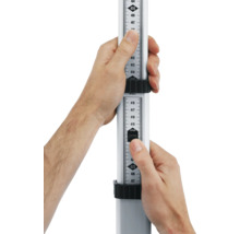 Dve ruky držia nivelačnú latu na meranie výšky.