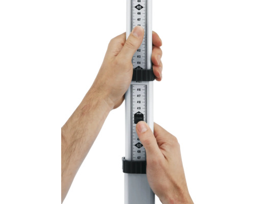 Dve ruky držia nivelačnú latu na meranie výšky.