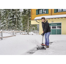 Muž odpratáva sneh pred domom pomocou snehovej frézy