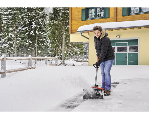 Muž odpratáva sneh pred domom pomocou snehovej frézy