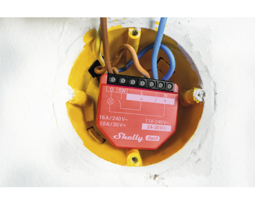 Detailný záber relé Shelly Gen3 v žltej zapustenej krabici s elektrickými vodičmi.