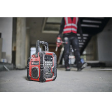 Stavebné rádio značky Einhell stojí na podlahe hrubej stavby.