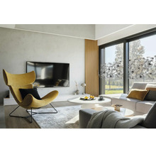 Svetlá obývacia izba s kreslom, sedačkou a okennou fóliou s rastlinným vzorom.