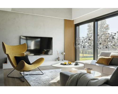 Svetlá obývacia izba s kreslom, sedačkou a okennou fóliou s rastlinným vzorom.