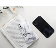 Dva kryty na mobilné telefóny s mramorovým vzorom ležia na otvorenej knihe.