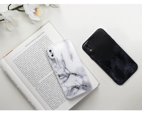 Dva kryty na mobilné telefóny s mramorovým vzorom ležia na otvorenej knihe.