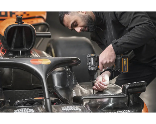 Muž pripevňuje diel k pretekárskemu autu pomocou akumulátorového skrutkovača