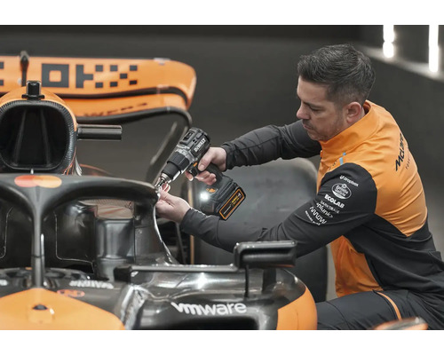 Mechanik používa akumulátorový skrutkovač na prácu na pretekárskom aute Formuly 1.