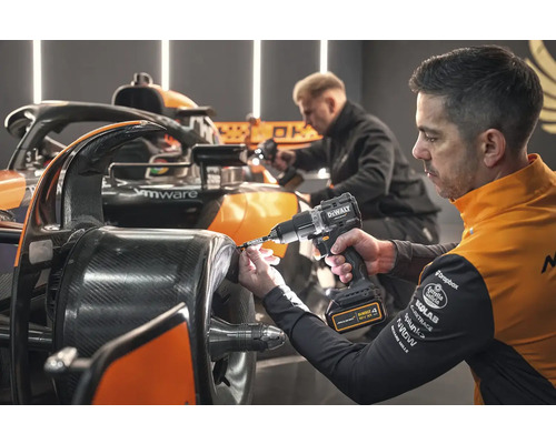 Muž montuje koleso na pretekárske auto pomocou akumulátorového skrutkovača.