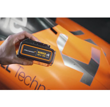 Batéria Dewalt 18 V XR 4 Ah v ruke pred vozidlom formuly 1 McLaren.