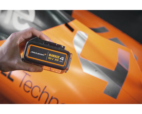 Batéria Dewalt 18 V XR 4 Ah v ruke pred vozidlom formuly 1 McLaren.