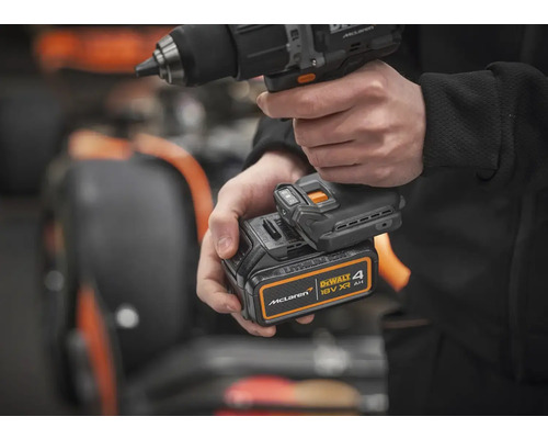 Osoba drží akumulátorový vŕtací skrutkovač s 18 V batériou