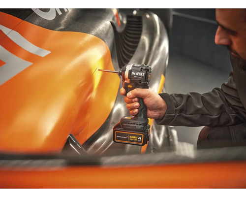 Remeselník s akumulátorovým rázovým uťahovákom DeWalt na oranžovom predmete