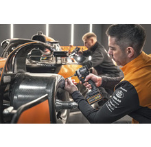 Mechanik pripevňuje diel k závodnému autu pomocou akumulátorového rázového uťahováka DeWalt.