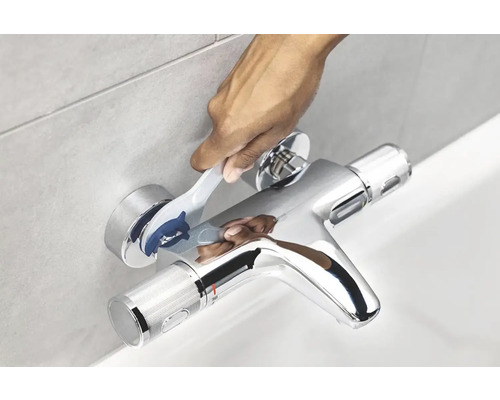 Ruka nastavuje vaňovú batériu na obloženej stene