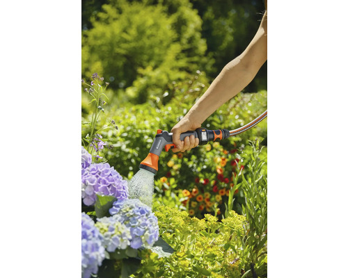 Osoba zalieva kvety záhradným zariadením Gardena.