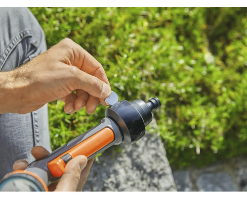 Osoba vkladá gombíkovú batériu do zavlažovacej pištole