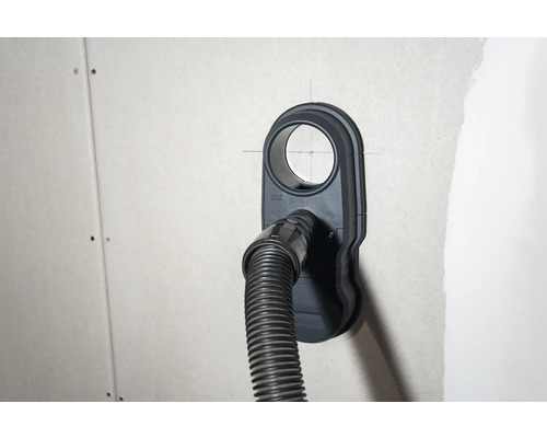 Zásuvka na pripojenie vysávača s pripojenou hadicou vysávača na stene