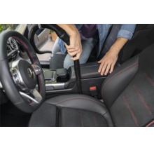 Osoba vysáva interiér automobilu pomocou vysávača