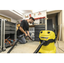 Muž používa žltý vysávač Kärcher v dielni na čistenie podlahy.