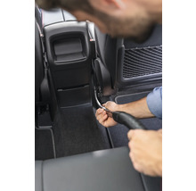 Osoba čistí interiér auta vysávačom.