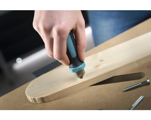 Ruka spúšťa zahlbovač značky Wolfcraft do drevenej dosky, aby zapustila skrutku.