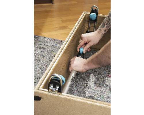 Muž upevňuje montážny uholník Wolfcraft do drevenej debny