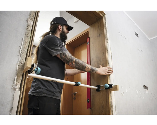 Muž montuje zárubňu pomocou montážneho nástroja