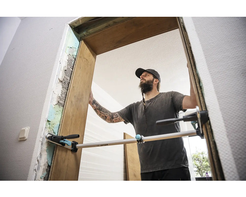 Remeselník montuje drevené dverové zárubne pomocou laty