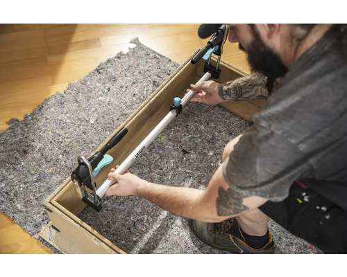 Remeselník upevňuje rozpínaciu tyč medzi dve strany dreveného rámu