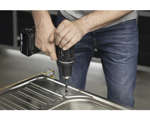 Muž vŕta do drezu akumulátorovým vŕtacím skrutkovačom