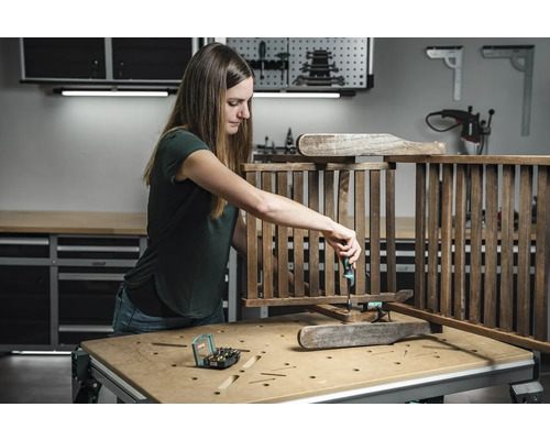 Žena montuje drevenú konštrukciu skrutkovačom v dielni