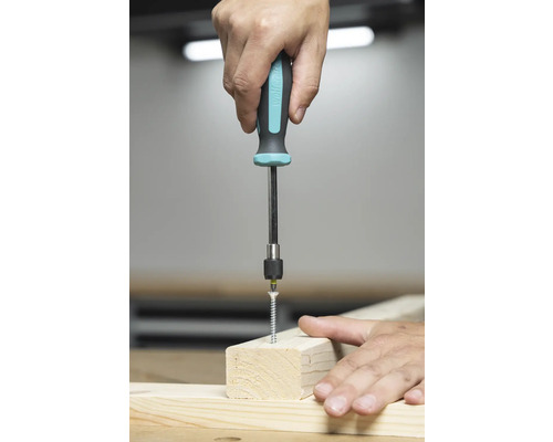 Osoba skrutkuje skrutku skrutkovačom do drevenej dosky