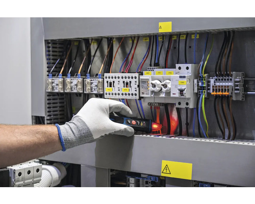 Elektrikár kontroluje rozvádzač pomocou skúšačky napätia