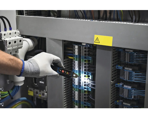 Elektrikár kontroluje rozvádzač pomocou skúšačky napätia