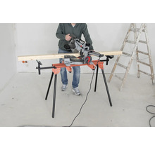 Osoba obsluhuje pokosovú pílu na rezacom stole vedľa rebríka.