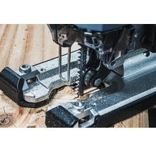 Detailný záber na priamočiaru pílu reznúcu drevo.