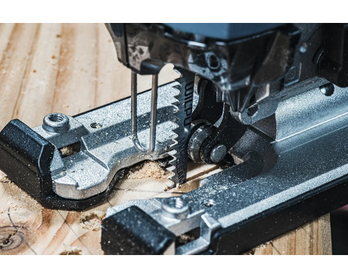 Detailný záber na priamočiaru pílu reznúcu drevo.