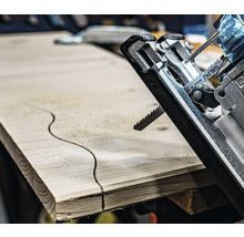 Detailný záber priamočiarej píly reže zakrivený vzor do drevenej dosky